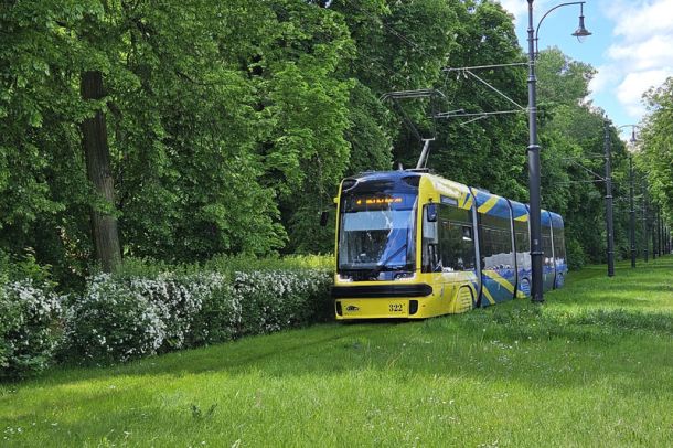 Żółto-niebieski tramwaj na zielonym torowisku